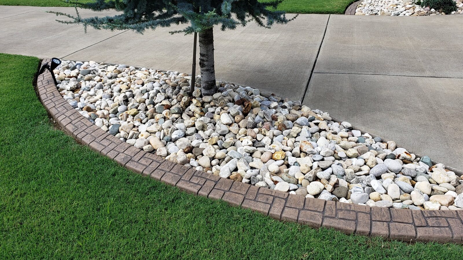 Brick-pattern curb around a white-rock tree island