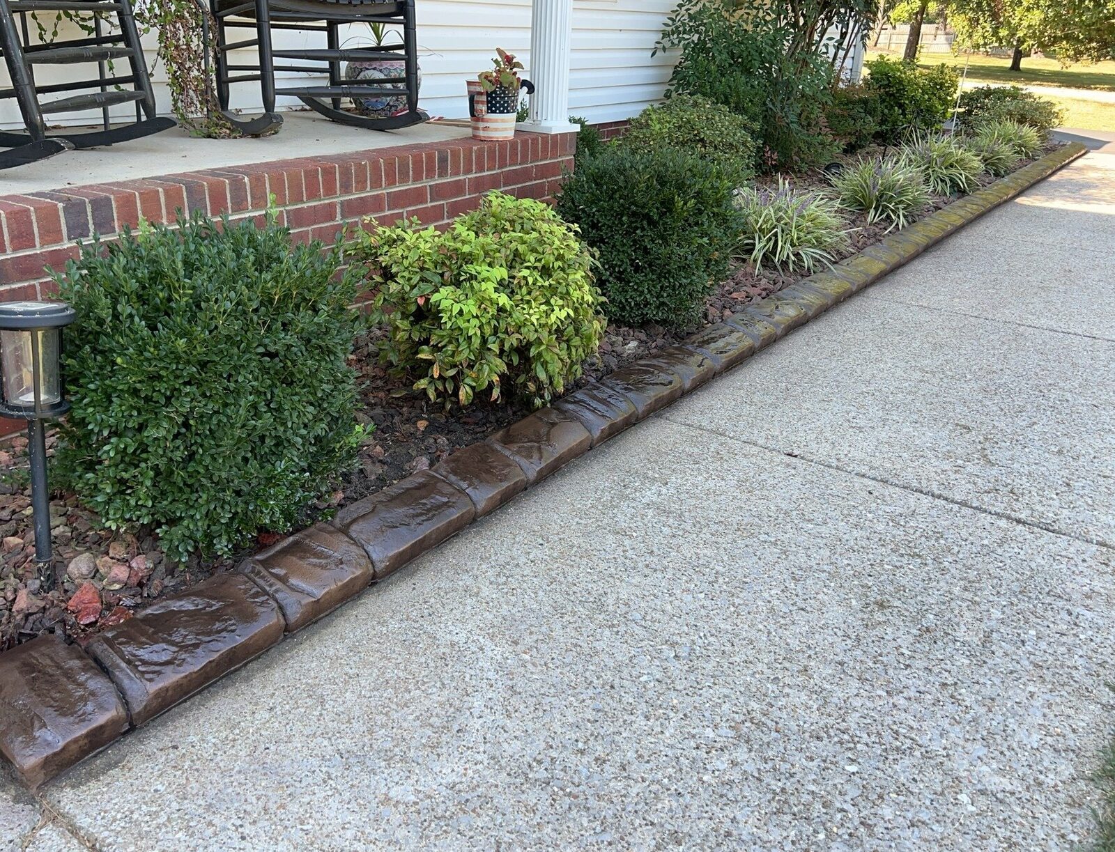 Brown stamped curbing holding a foundation bed back from a driveway, stamped concrete in Murfreesboro, TN