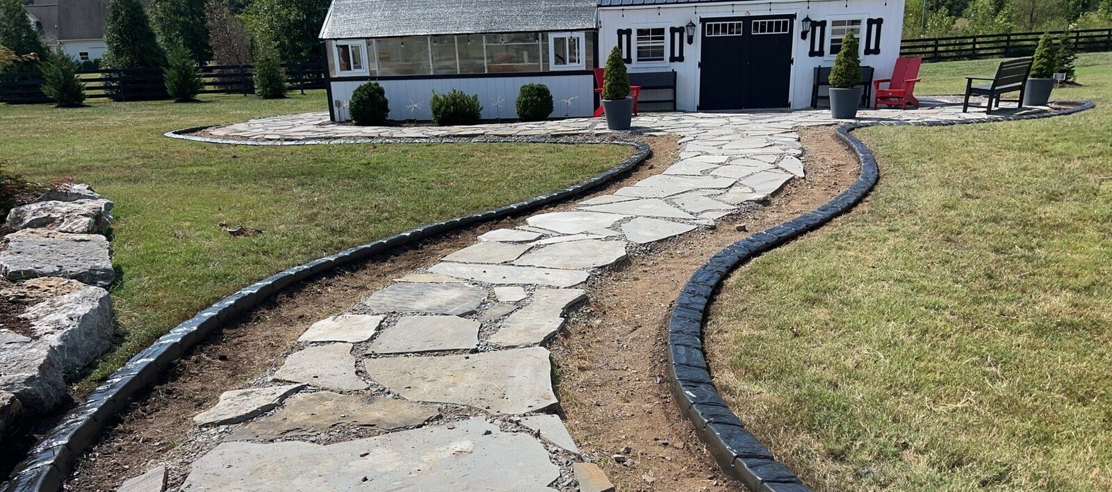 Dark stamped curbing edging a flagstone path that curves up to a garden shed