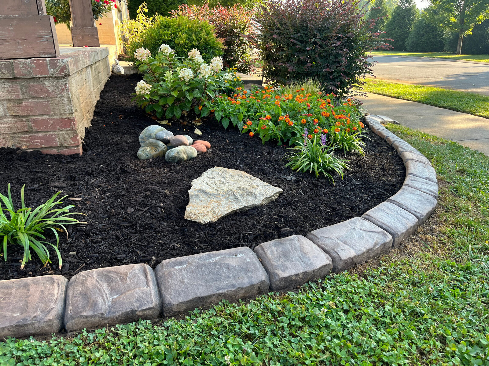 Dark stamped concrete curbing around a black-mulch flower bed
