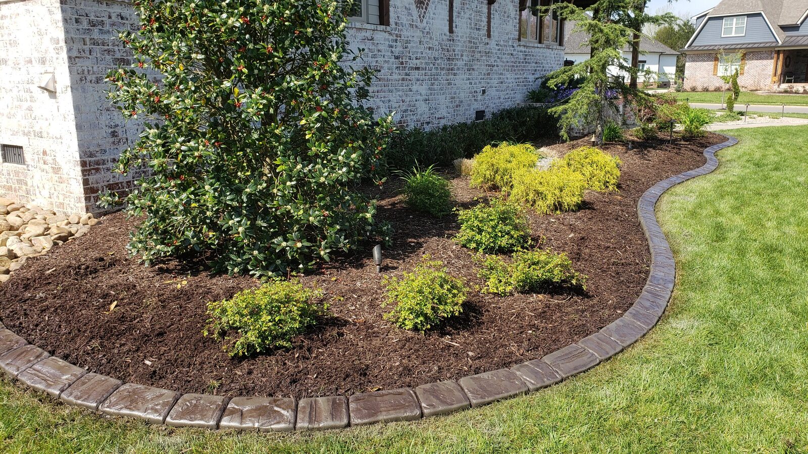Finished dark stamped curb along a foundation shrub bed
