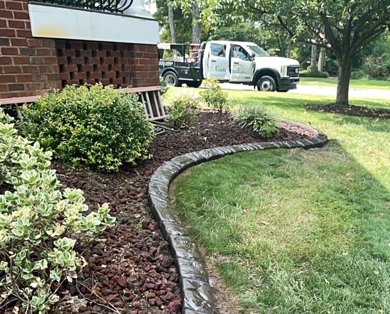 A freshly sealed curb around a lava-rock bed