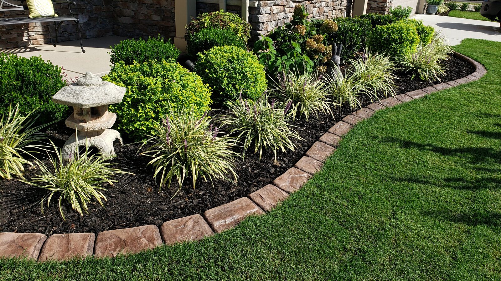 Tan stamped curbing around a garden bed with a stone lantern